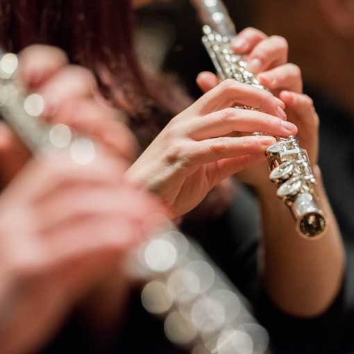 Close-up image of two people playing flute