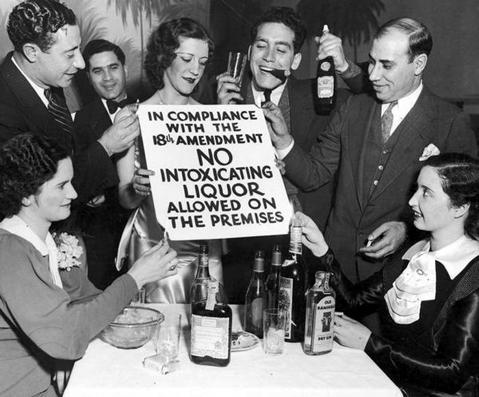 A group celebrating the end of Prohibition with four people setting fire to the four corners  of the sign.