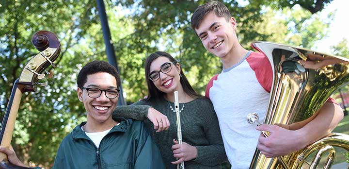Three high school-aged musicians pose with their instruments