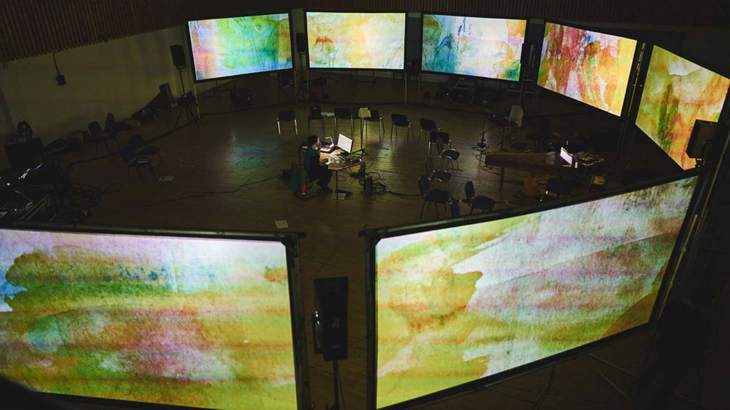Musician on stage surrounded by screens